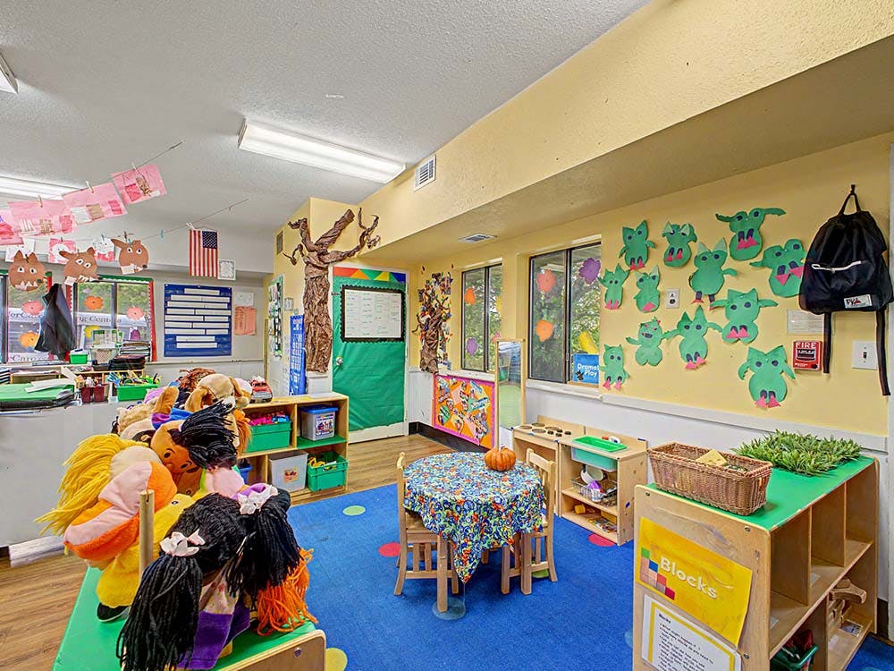 Classroom with colorful decorations, small tables, chairs, and cubbies