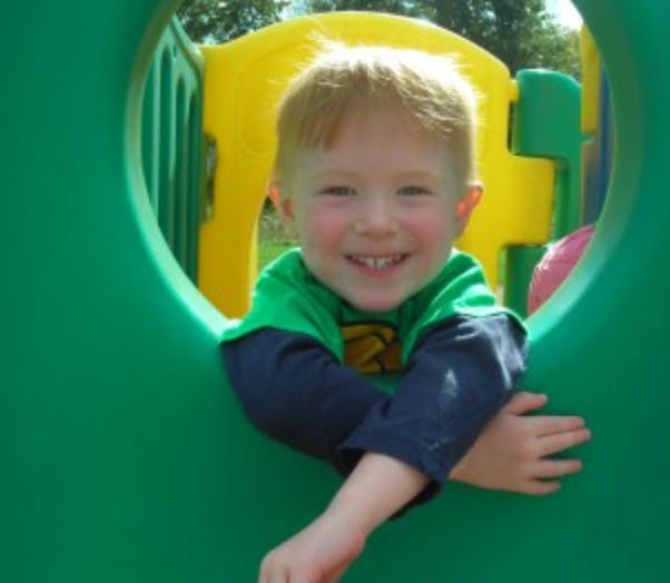 Child in a green and yellow playground structure