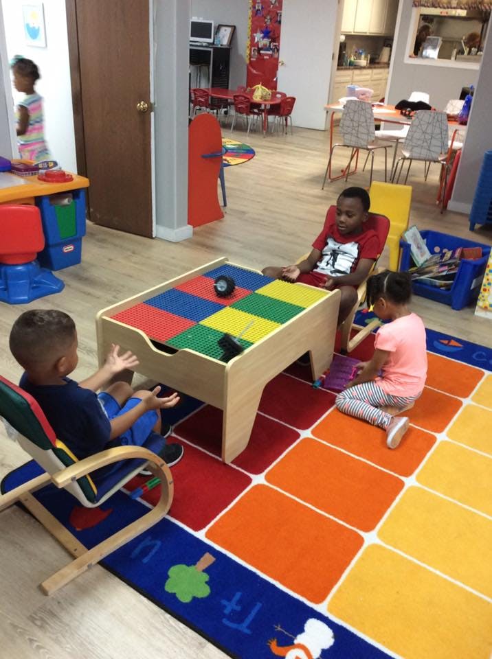 Three children playing at a table in a classroom