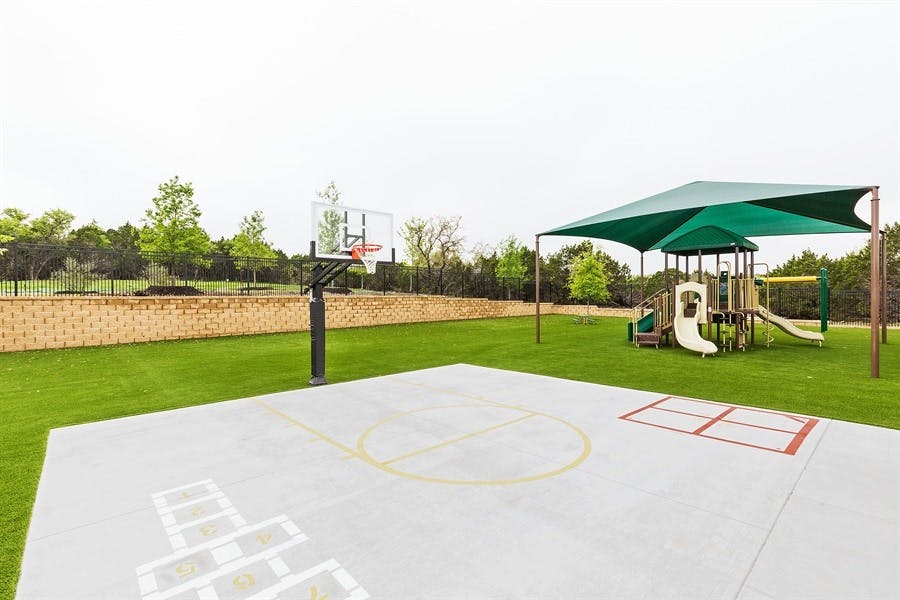 Outdoor basketball court and playground with a green shade canopy