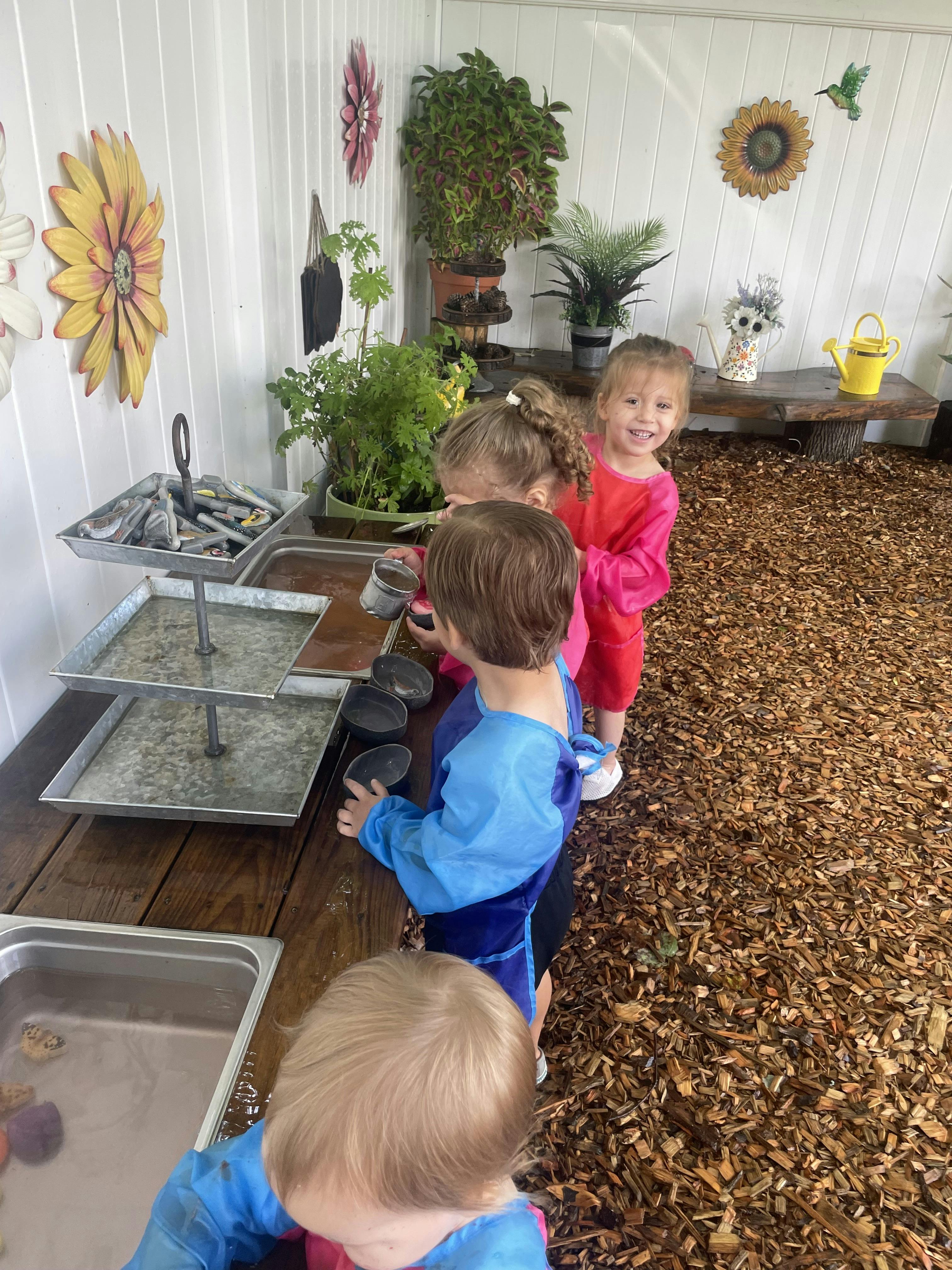 Children playing with trays and cups on a wooden surface