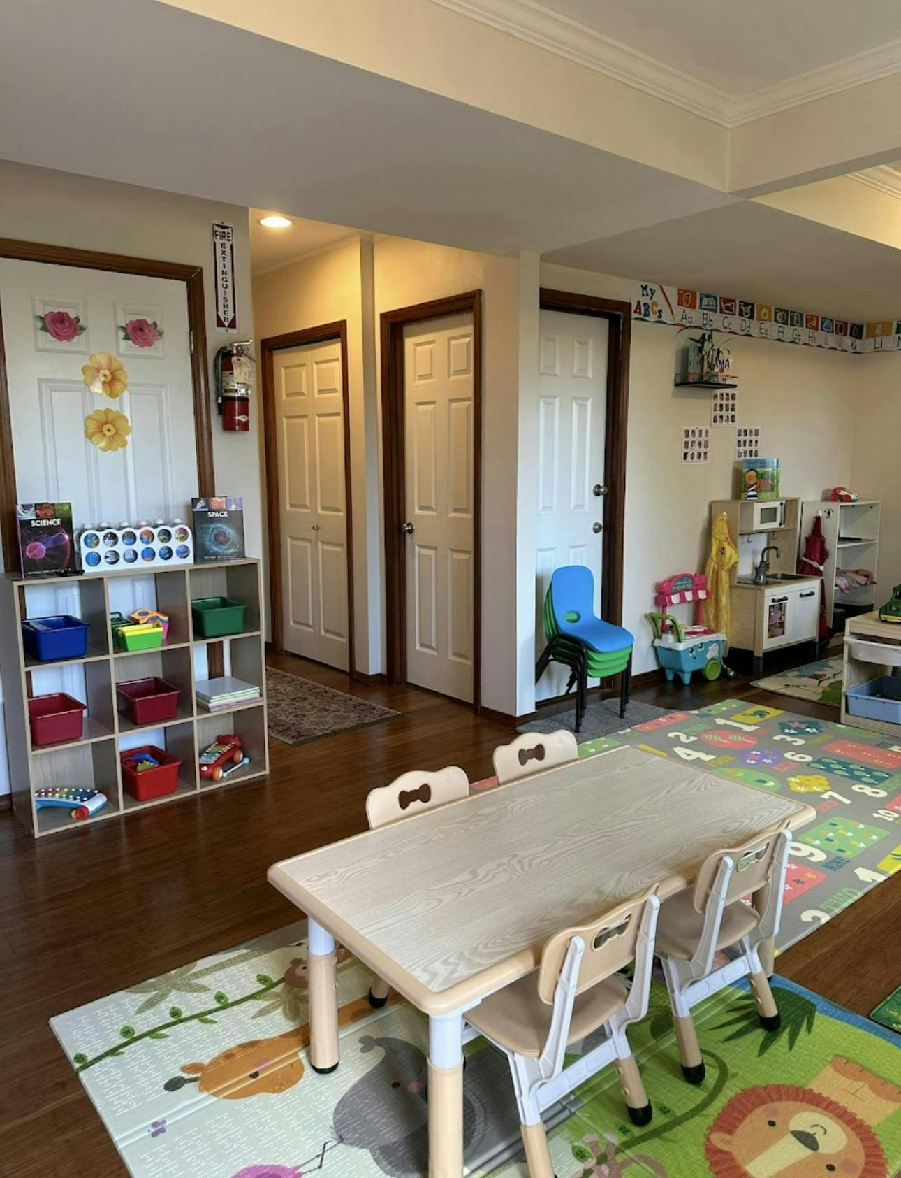 Children's play area with small table and chairs, toy kitchen, and storage shelves