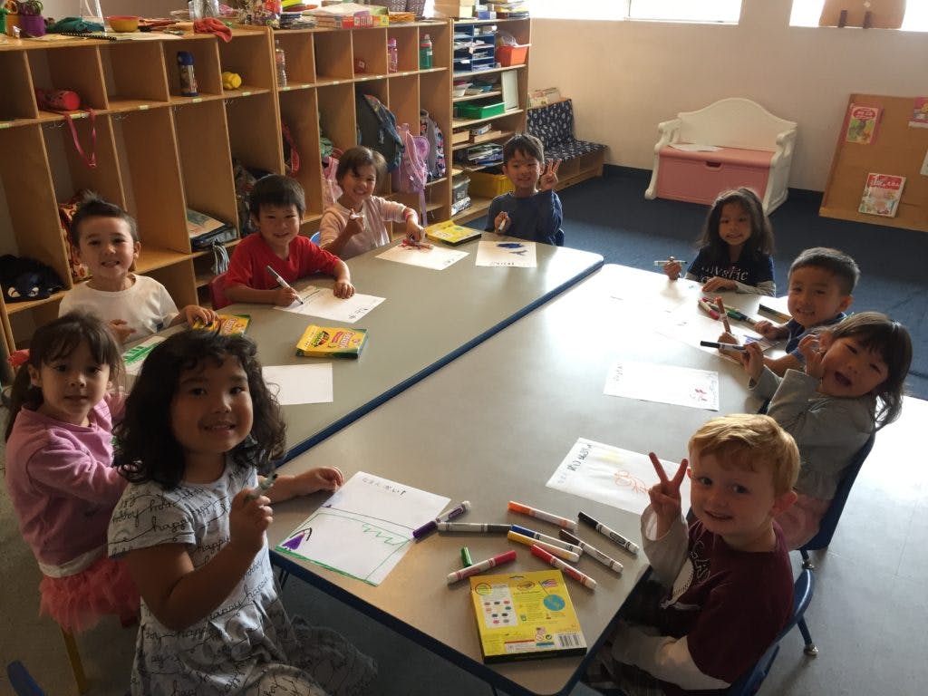 Children sitting at tables drawing in a classroom