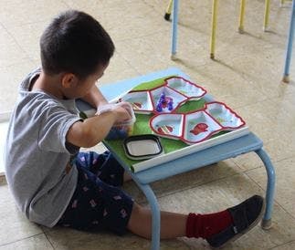 Child playing with a sorting tray on a small table