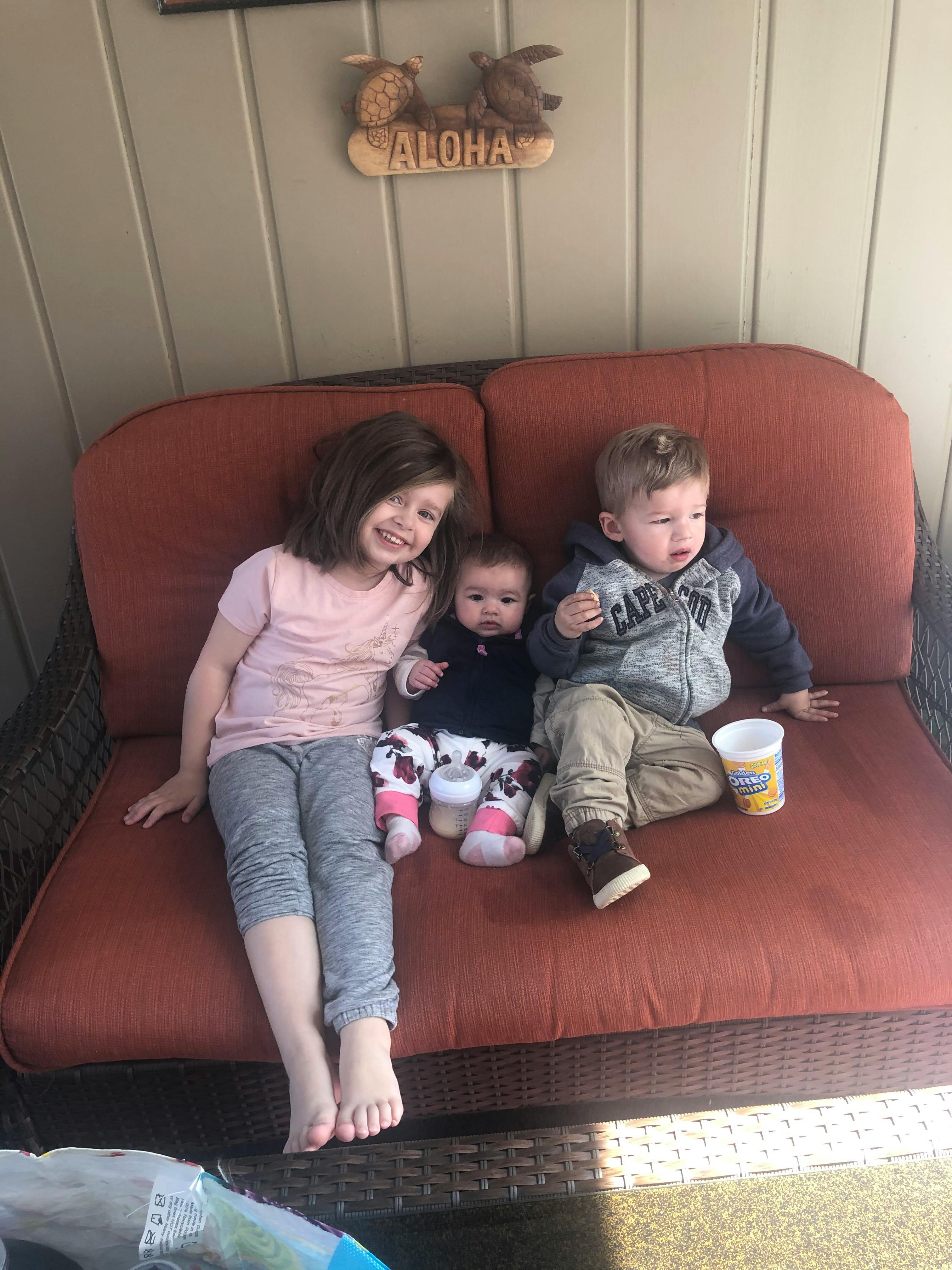 Three children sitting on an outdoor couch