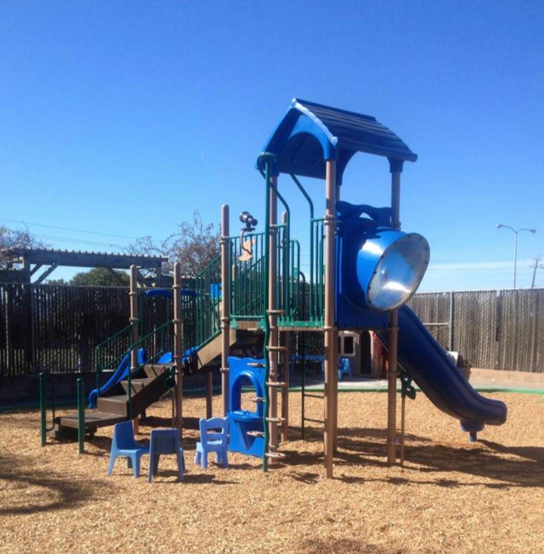 Playground with blue slides and climbing structures on wood chips