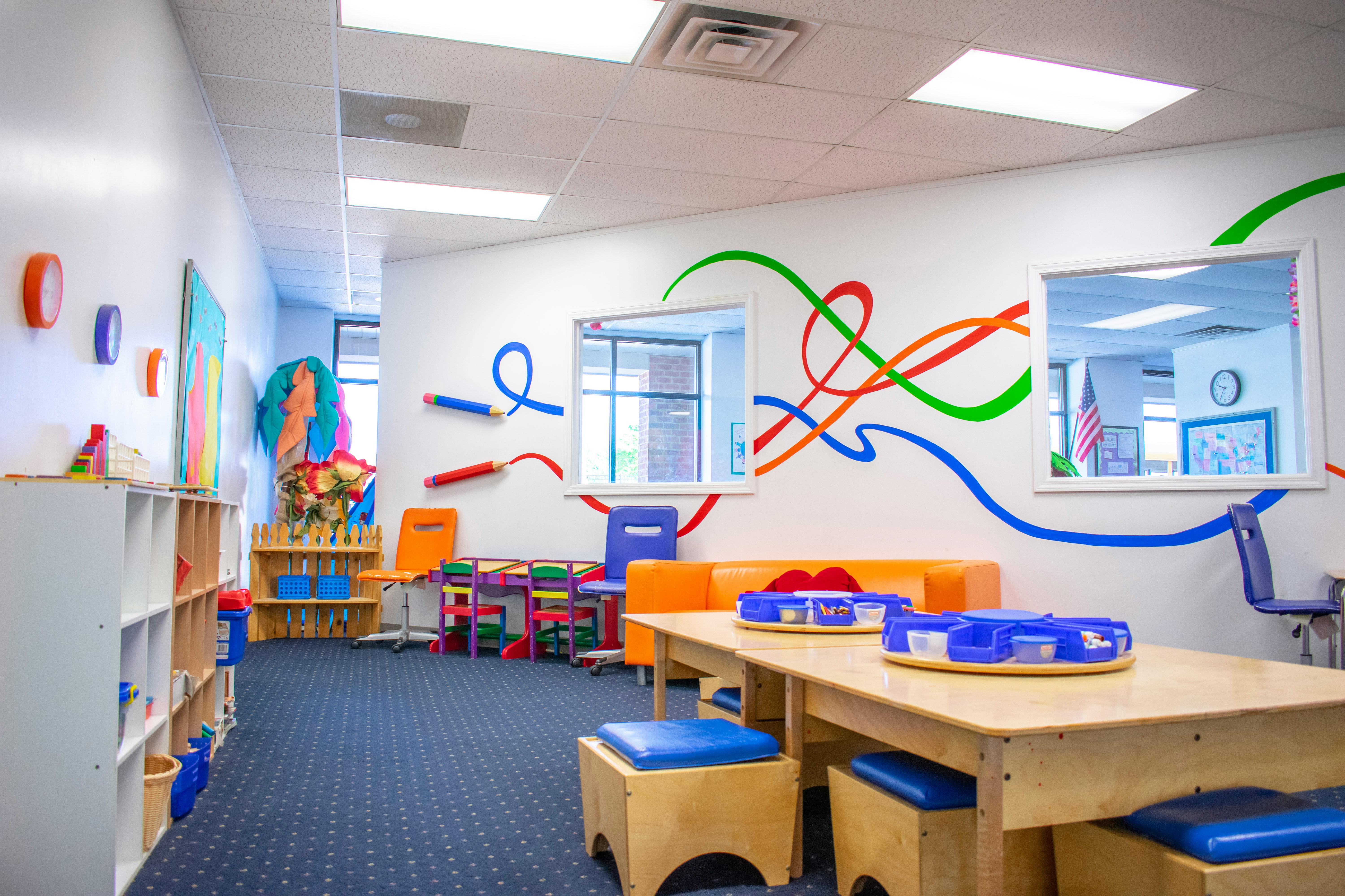 Playroom with colorful wall decorations, tables, and chairs
