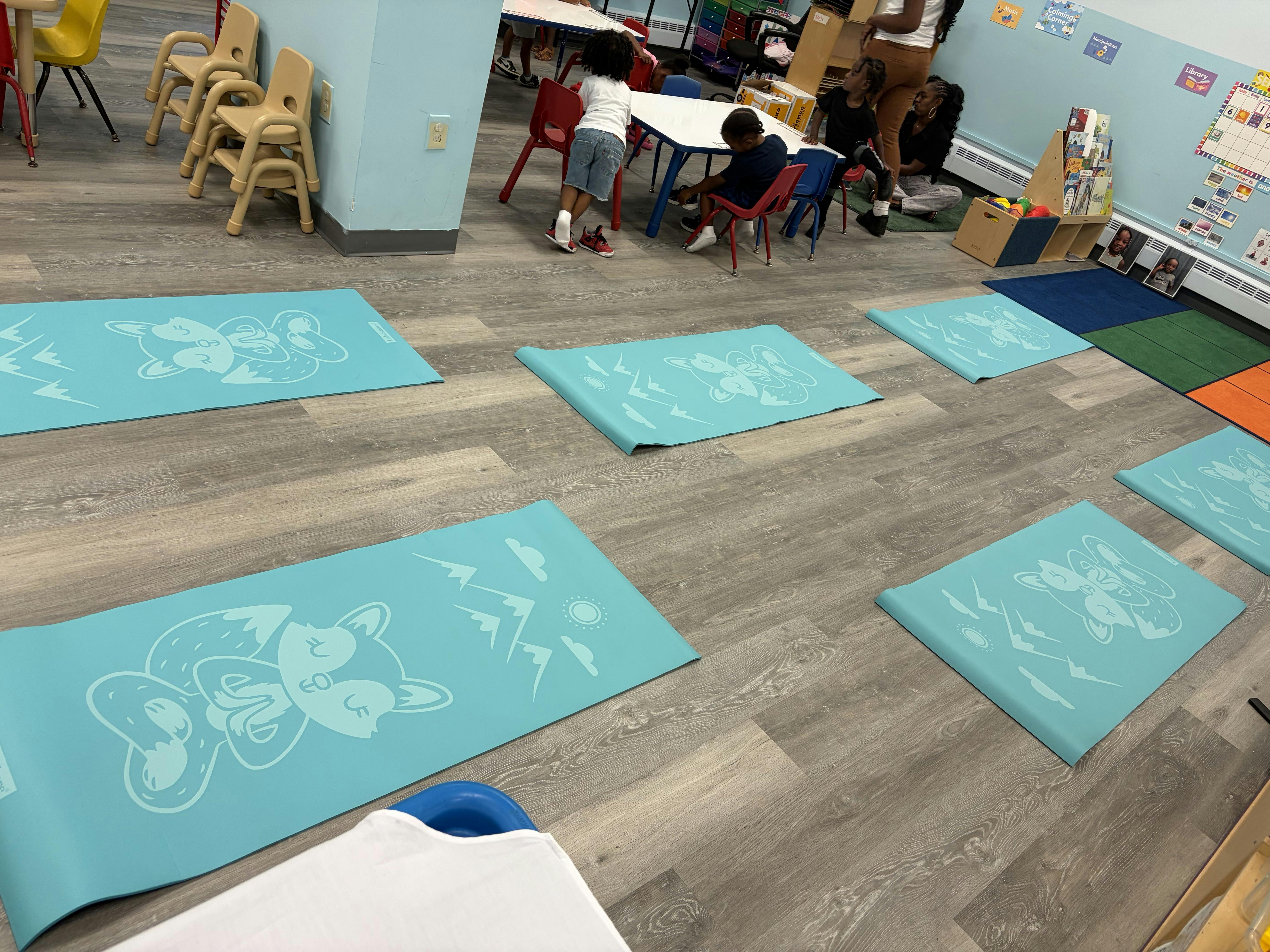 Light blue yoga mats with fox illustrations arranged on a classroom floor