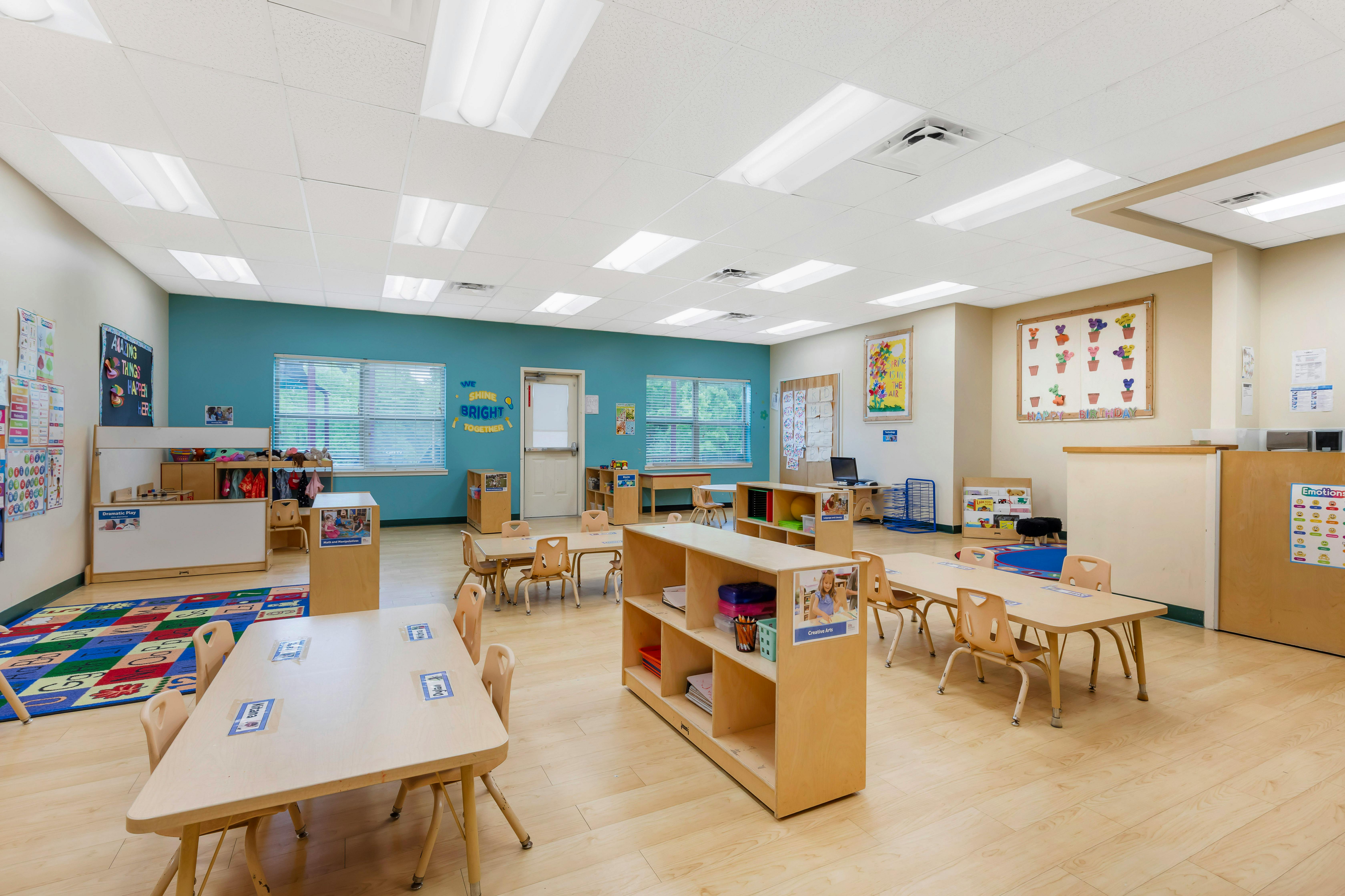 Empty preschool classroom with small tables and chairs