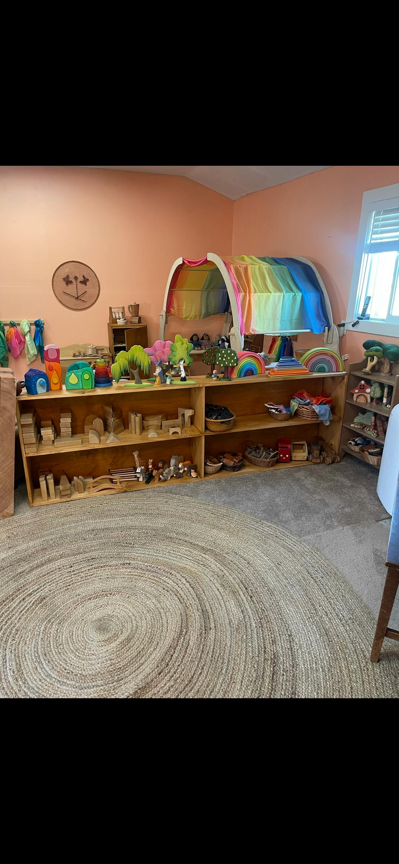 Classroom with shelves of toys and a rainbow play tent