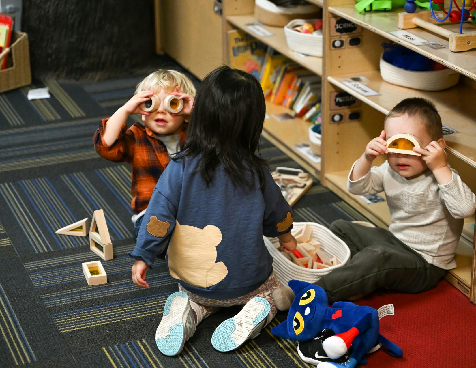 Three children playing with toys in a classroom