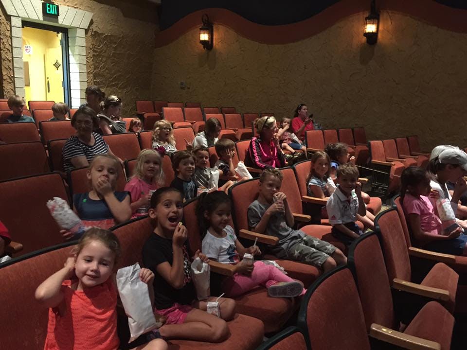 Many children sitting in an auditorium watching a performance