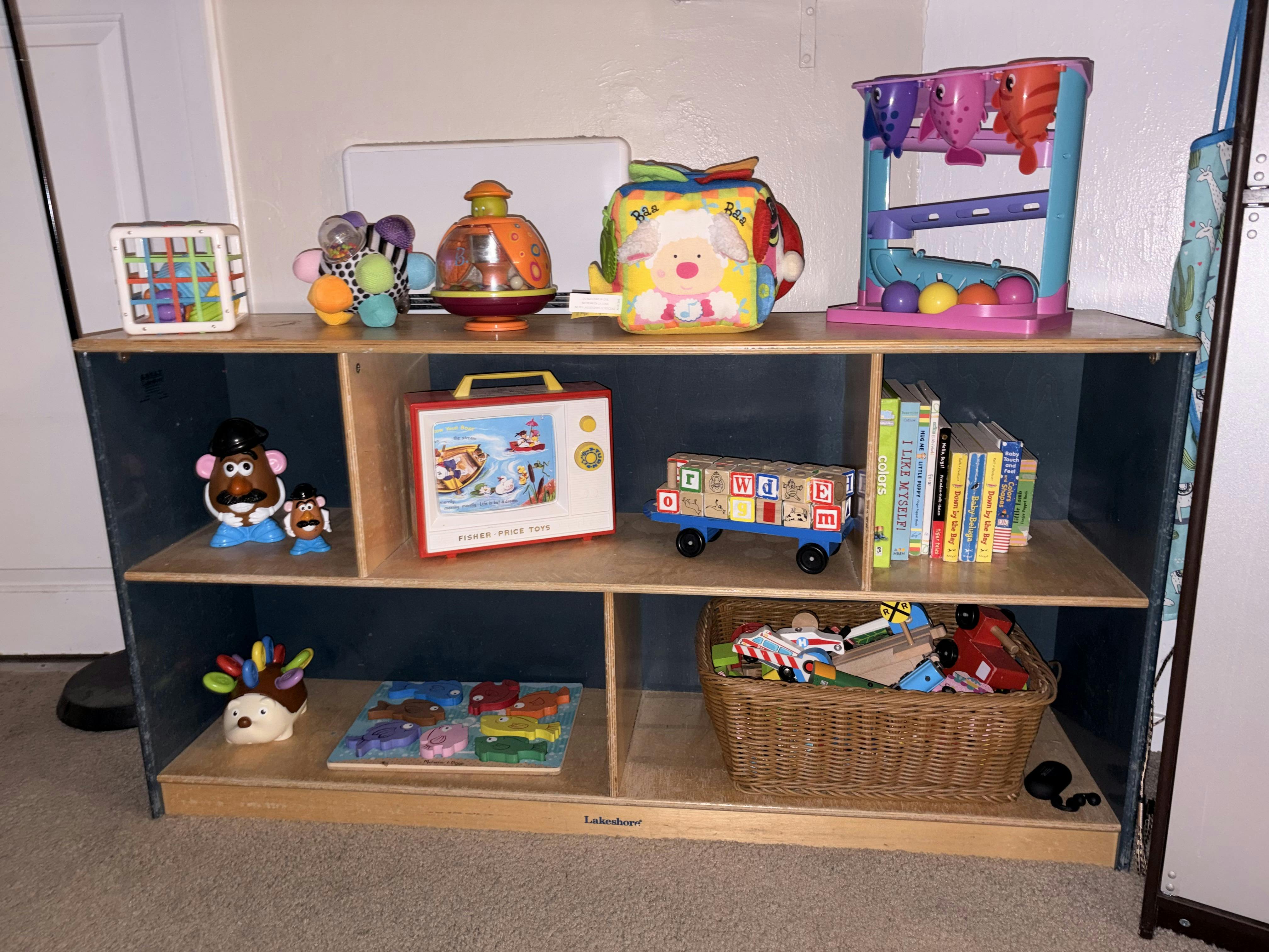 Children's toys on a wooden shelf including Mr. Potato Head, books, and puzzles