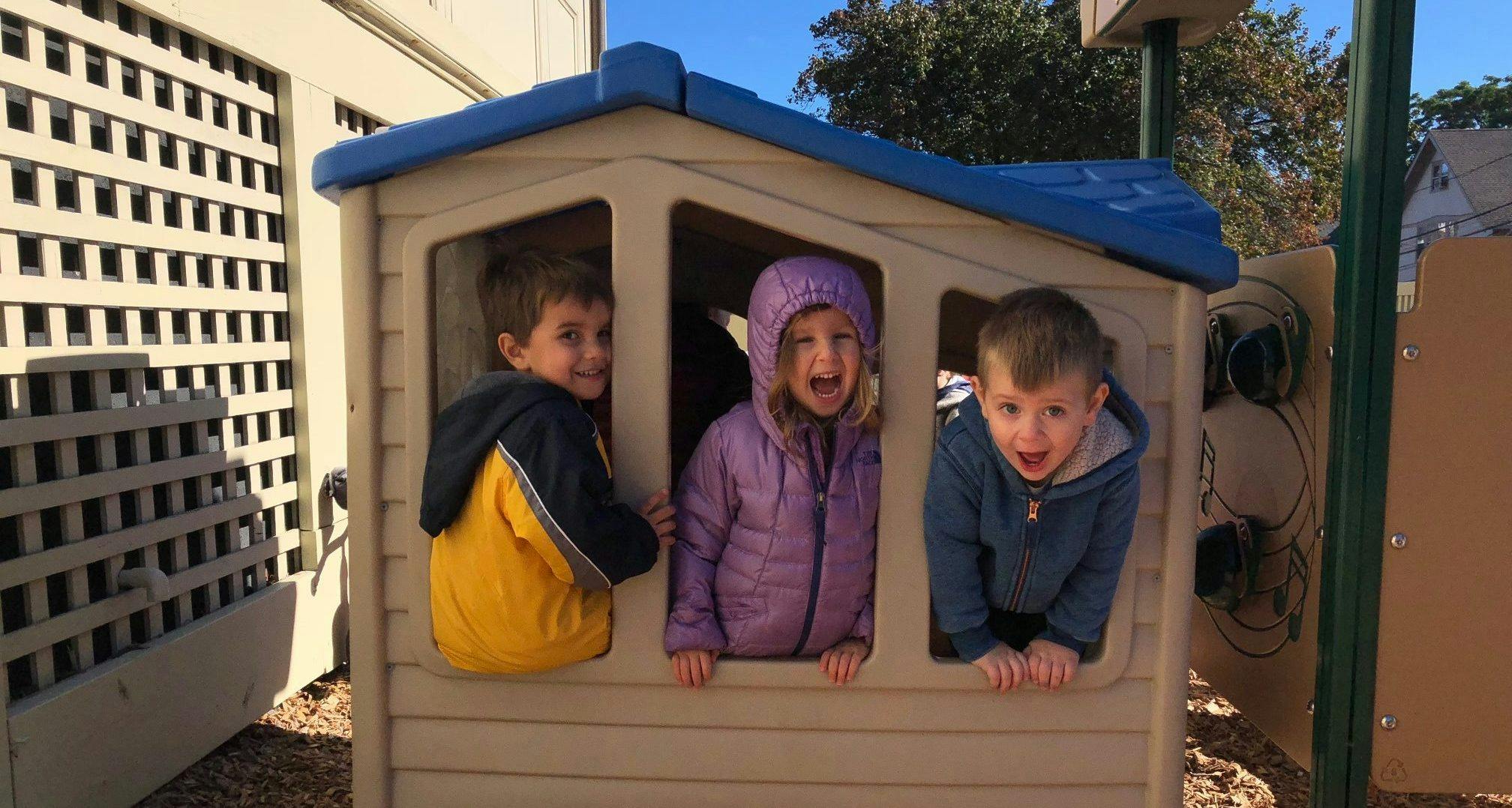Three children looking out of a playhouse window