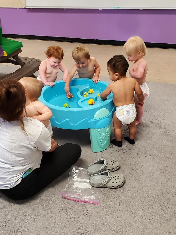 Person and multiple children playing with a water table