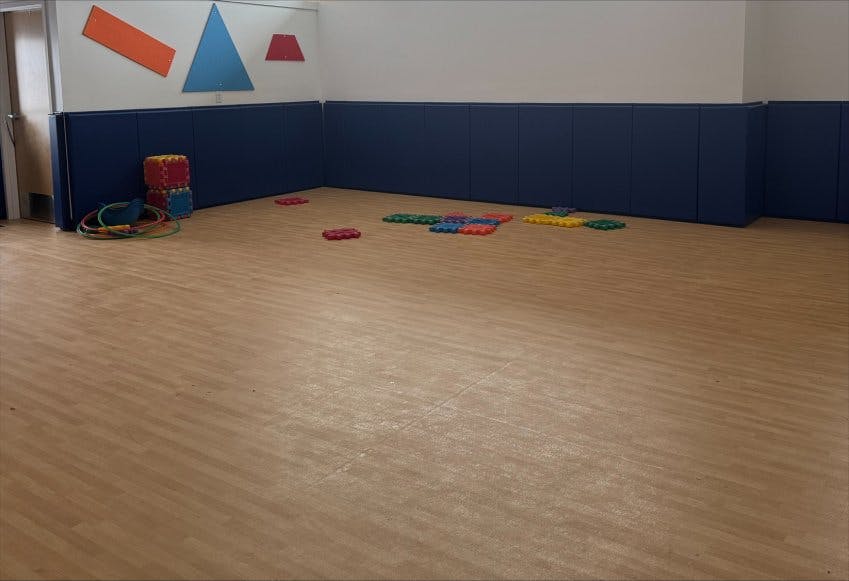 Empty playroom with blue padded walls and colorful play mats on the floor