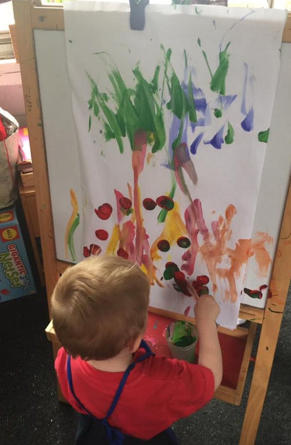 Child finger painting on an easel
