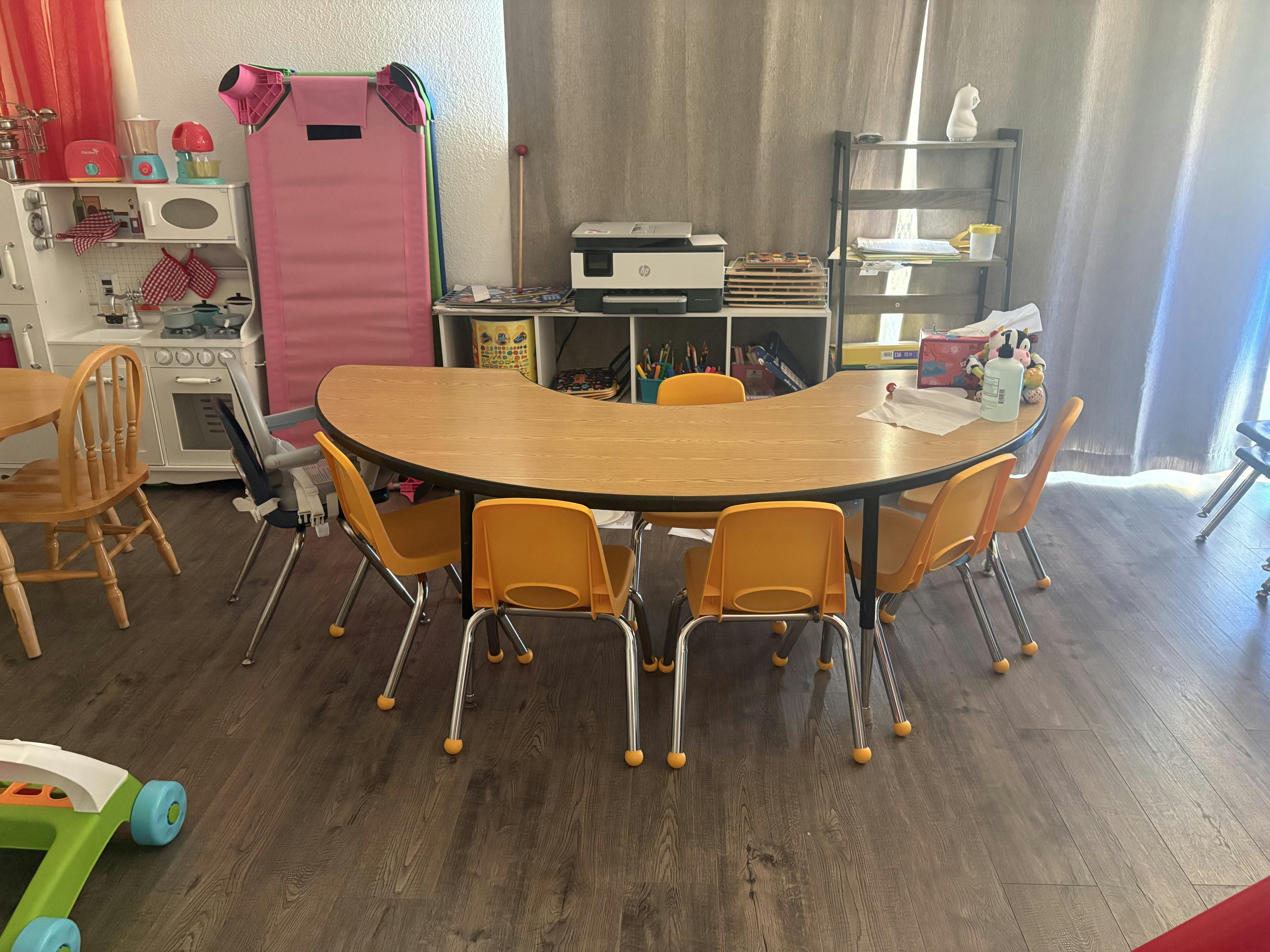 Classroom with child-sized furniture, including a curved table and orange chairs