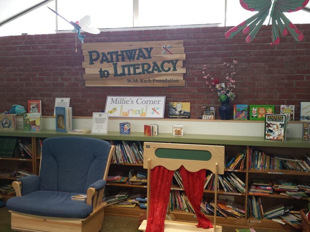 Library area with bookshelves, a blue chair, and a puppet stage