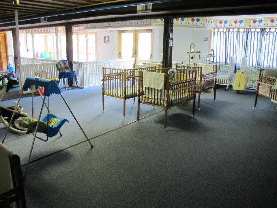 Room with multiple cribs and a baby swing