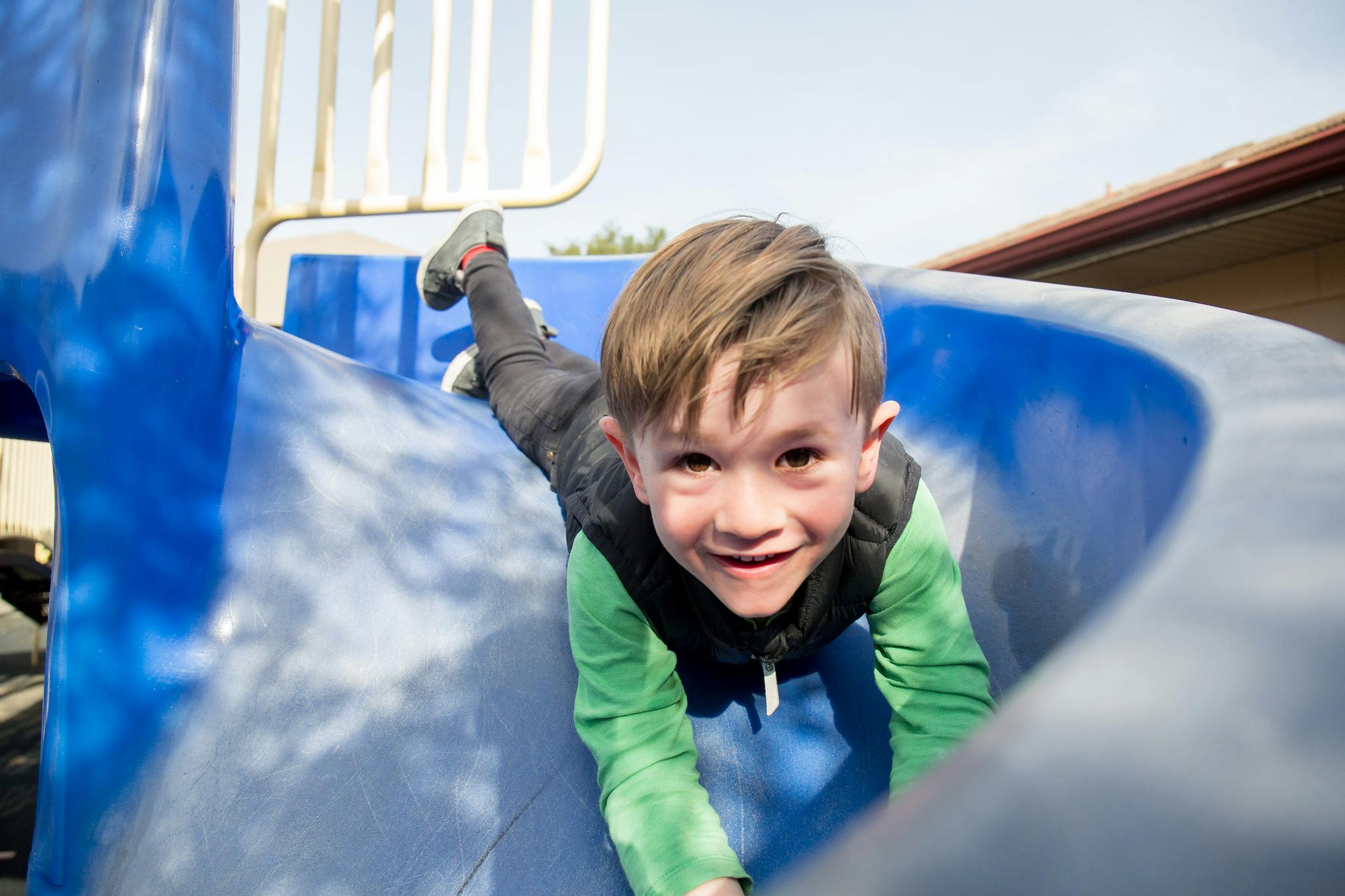 Child on a blue playground slide