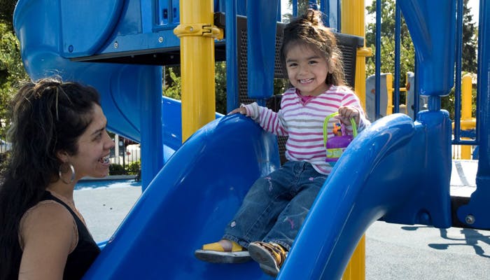 Person looking at child sitting on a playground slide