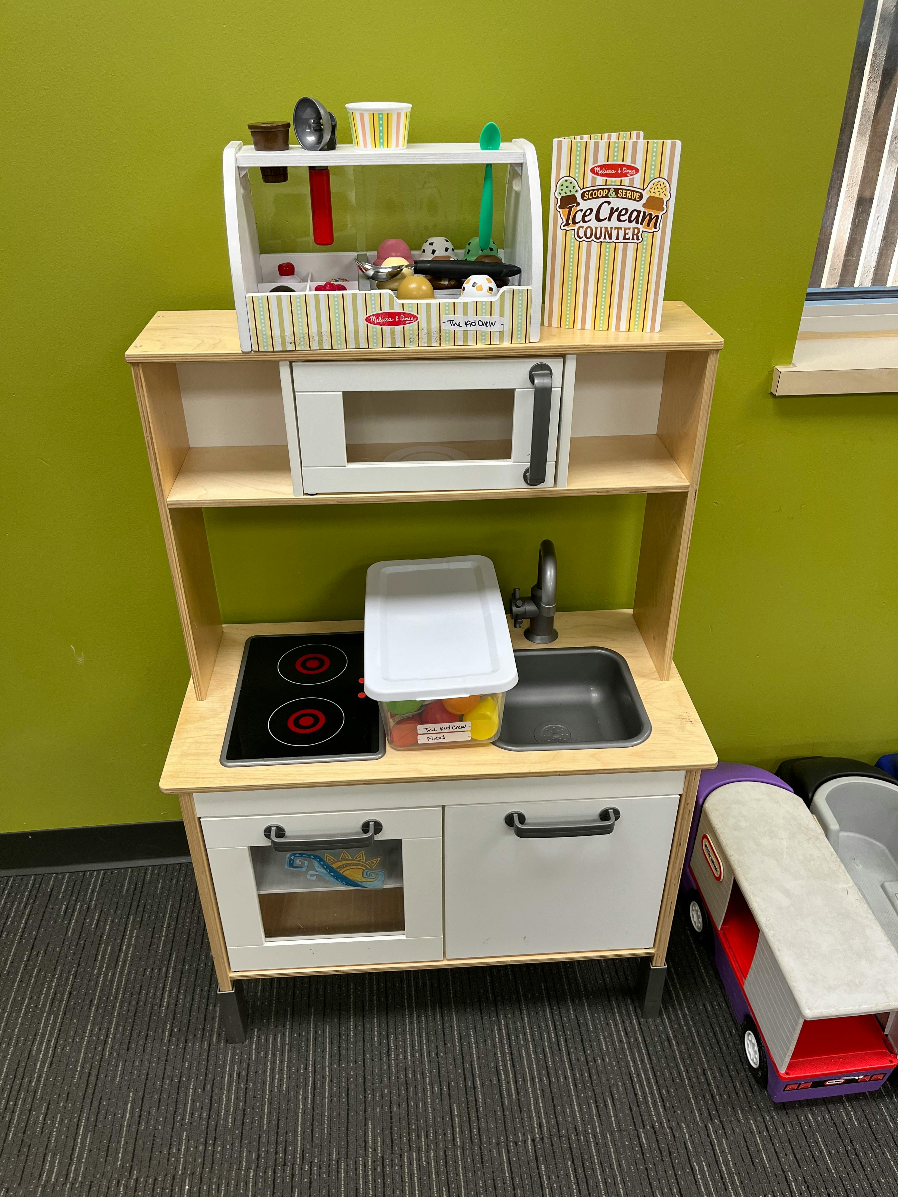 Toy kitchen set with a microwave, stove, sink, and ice cream counter