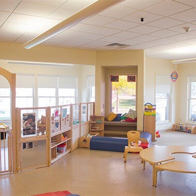 Empty classroom with small tables, chairs, and shelves