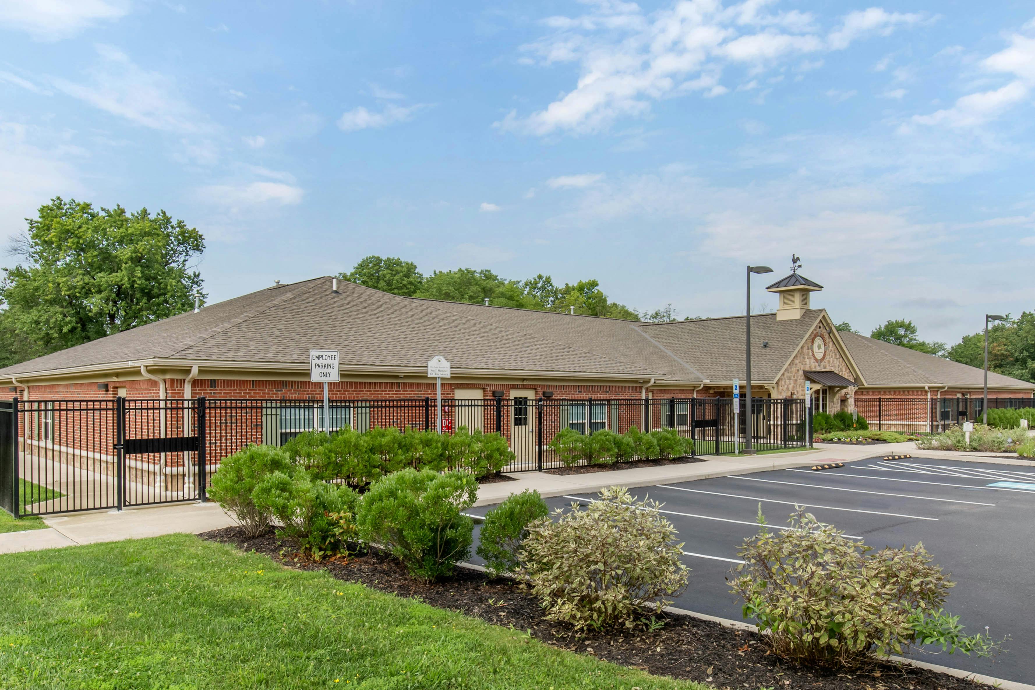 Brick building with a parking lot in front and green trees