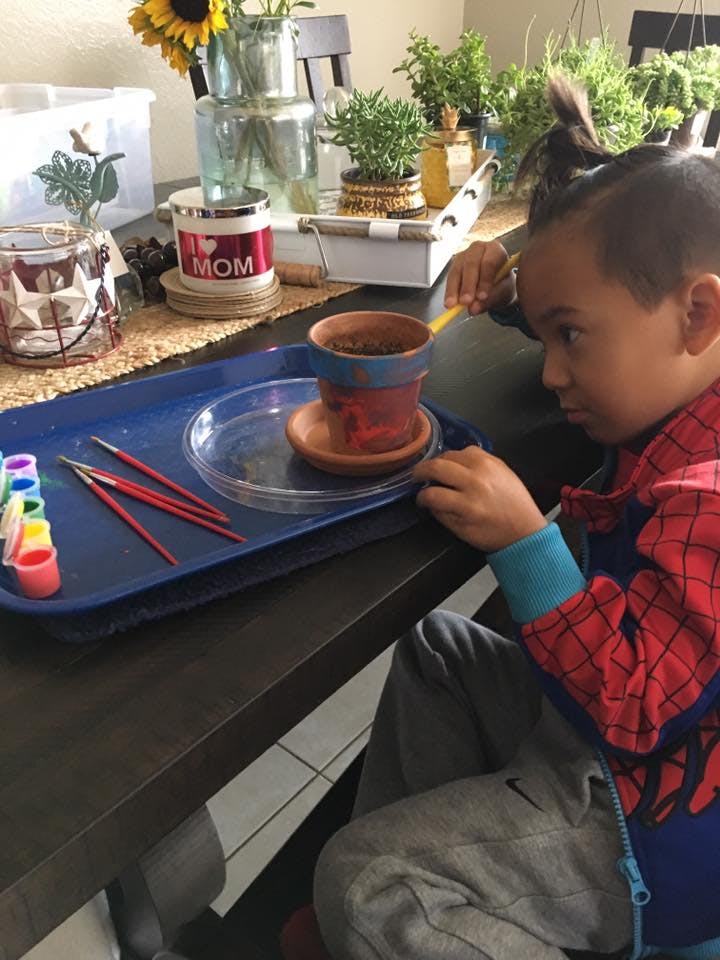 Child painting a small terracotta pot