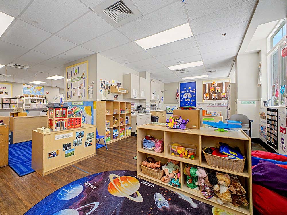 Classroom with toys, cubbies, and a solar system rug