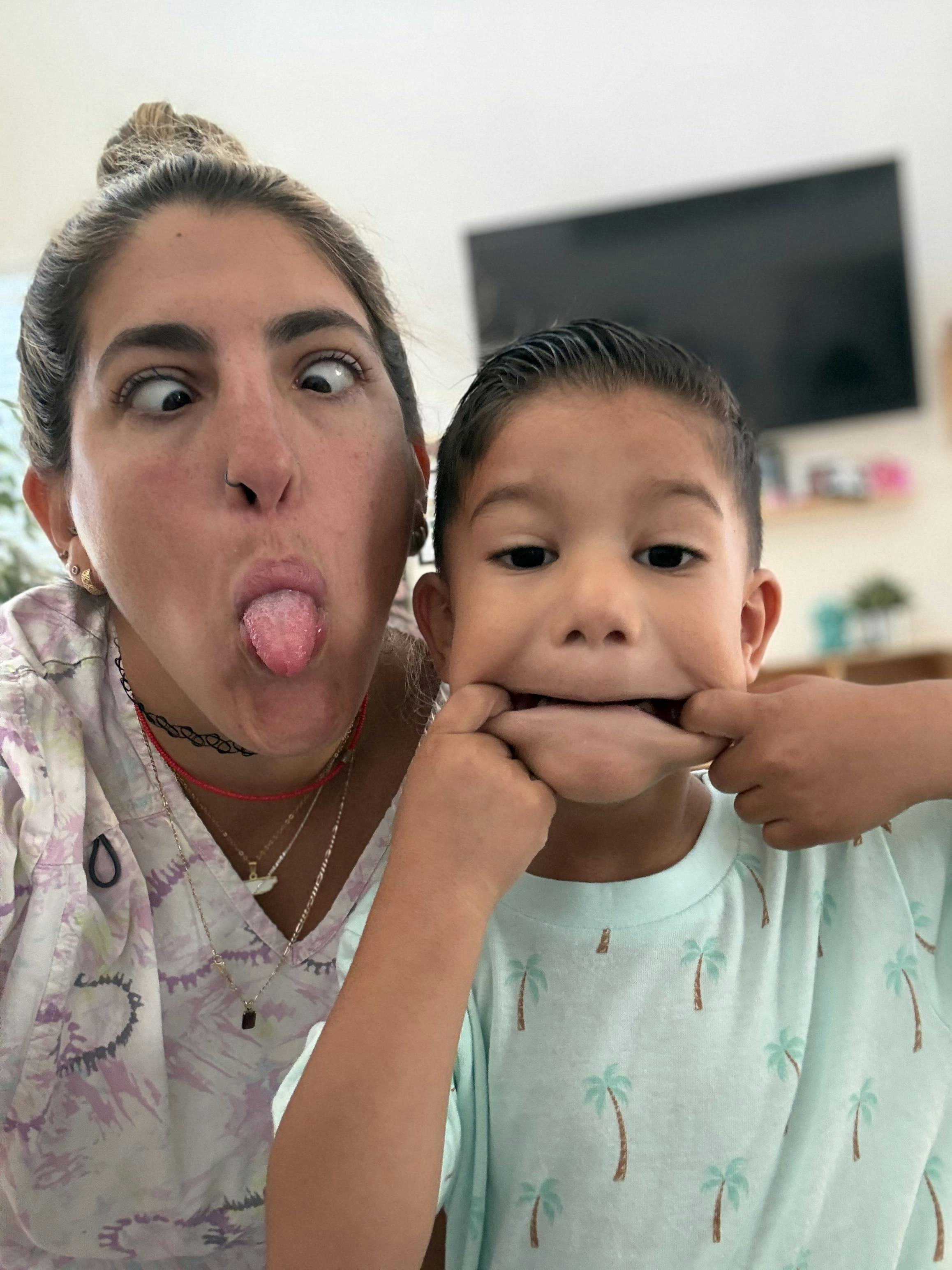 Person with eyes crossed and tongue out next to a child pulling at their cheeks
