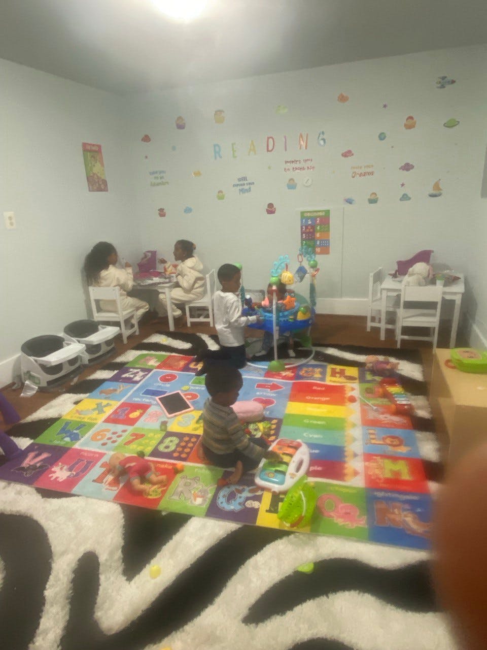 Children playing in a room with a colorful alphabet rug
