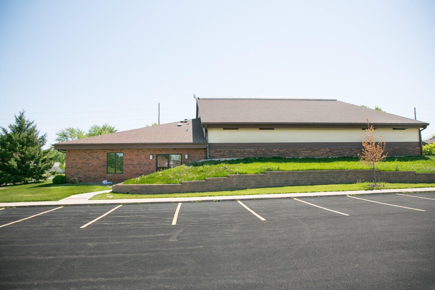 Building with brick and light-colored siding next to a parking lot