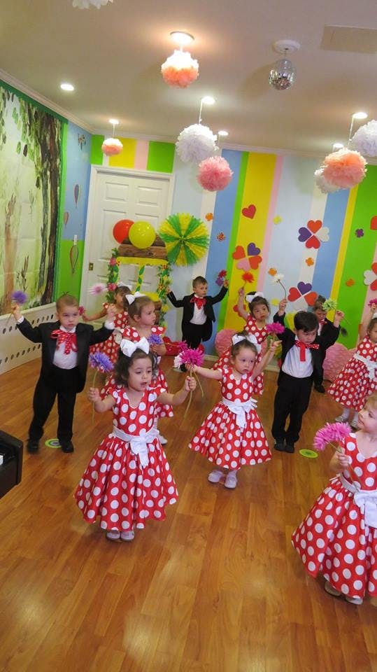 Children in red and white polka dot dresses and black tuxedos dancing