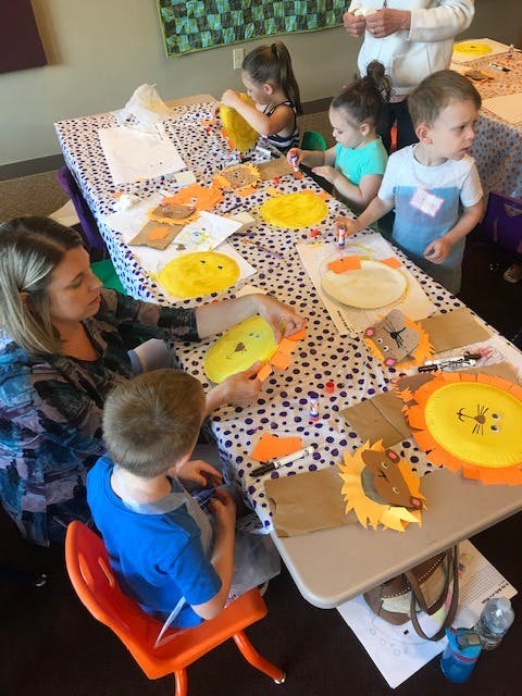 People and children making lion crafts at a table