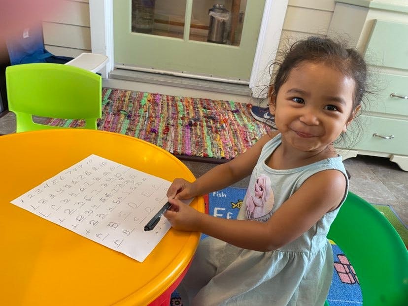 Child sitting at a table with a paper and pen