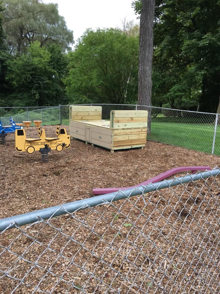 Playground with a wooden sandbox and a yellow spring rider