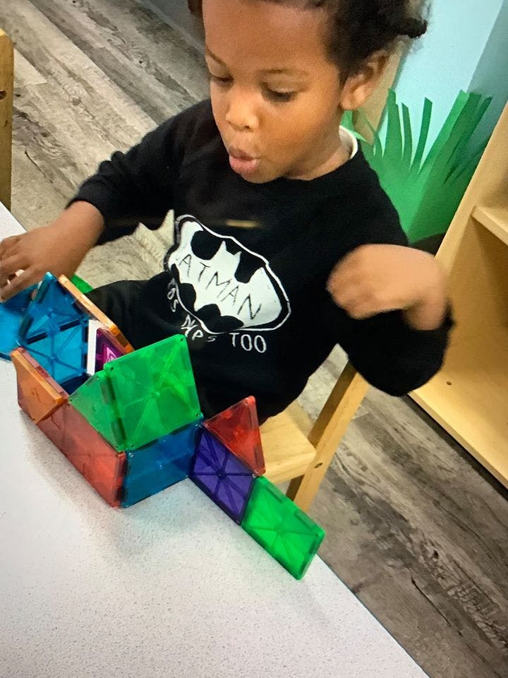 Child playing with colorful magnetic tiles on a table