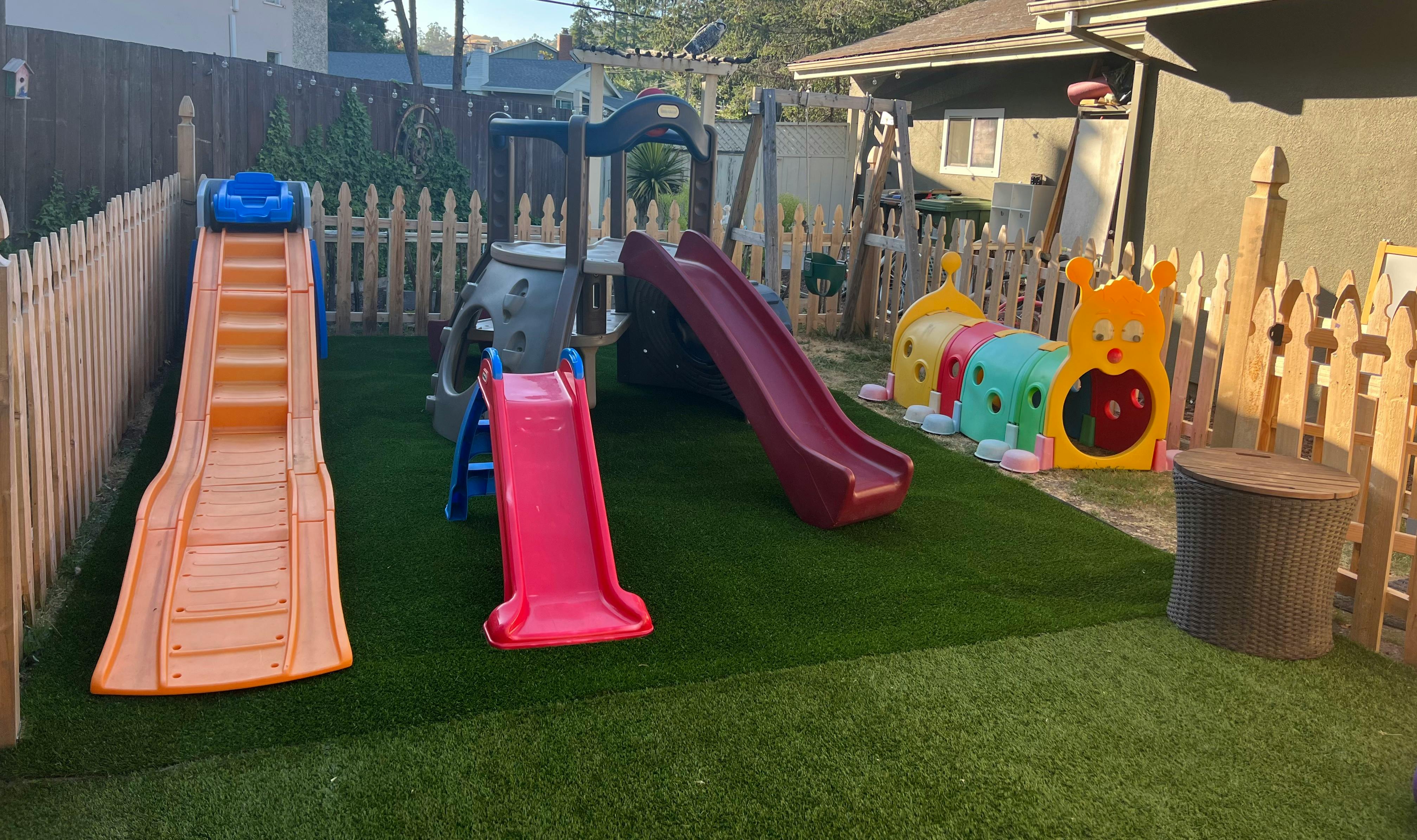 Outdoor playground with multiple slides and play structures on artificial turf