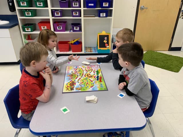 Four children playing a board game at a table