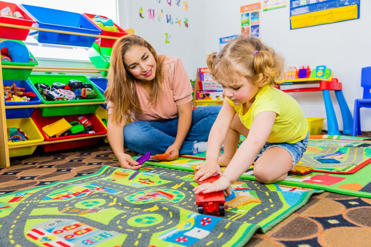 Adult and child playing with toy car on a road map rug