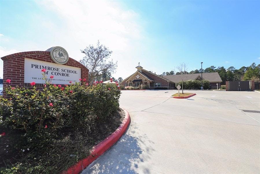 Brick sign for Primrose School of Conroe with building in background