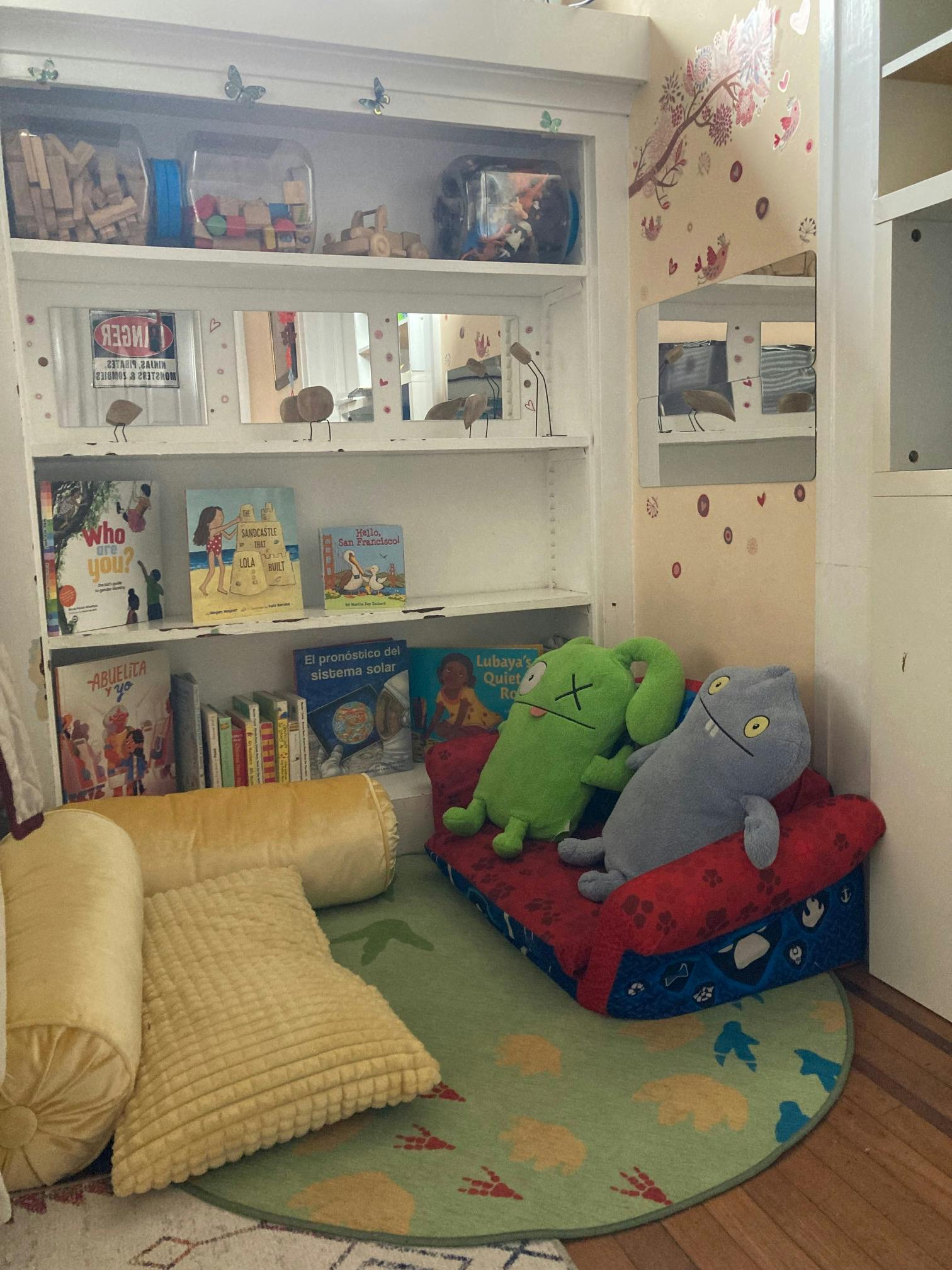 Bookshelf with books and toys, two stuffed animals on a small couch