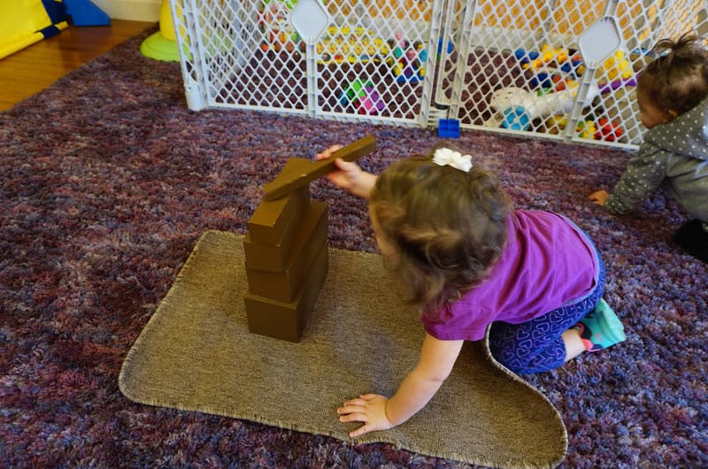 Child playing with wooden blocks on a rug