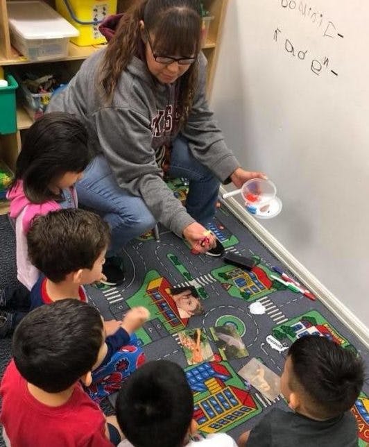 Person and children playing with small objects on a rug