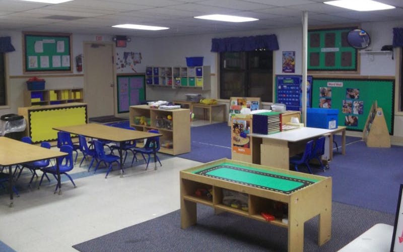 Empty classroom with tables, chairs, and shelves of learning materials