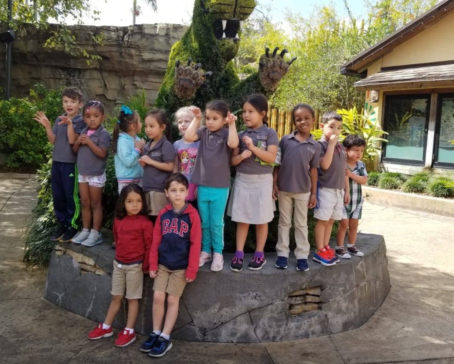 Group of children standing in front of a large green topiary
