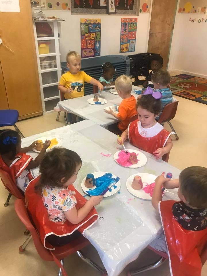 Children painting at tables in a classroom
