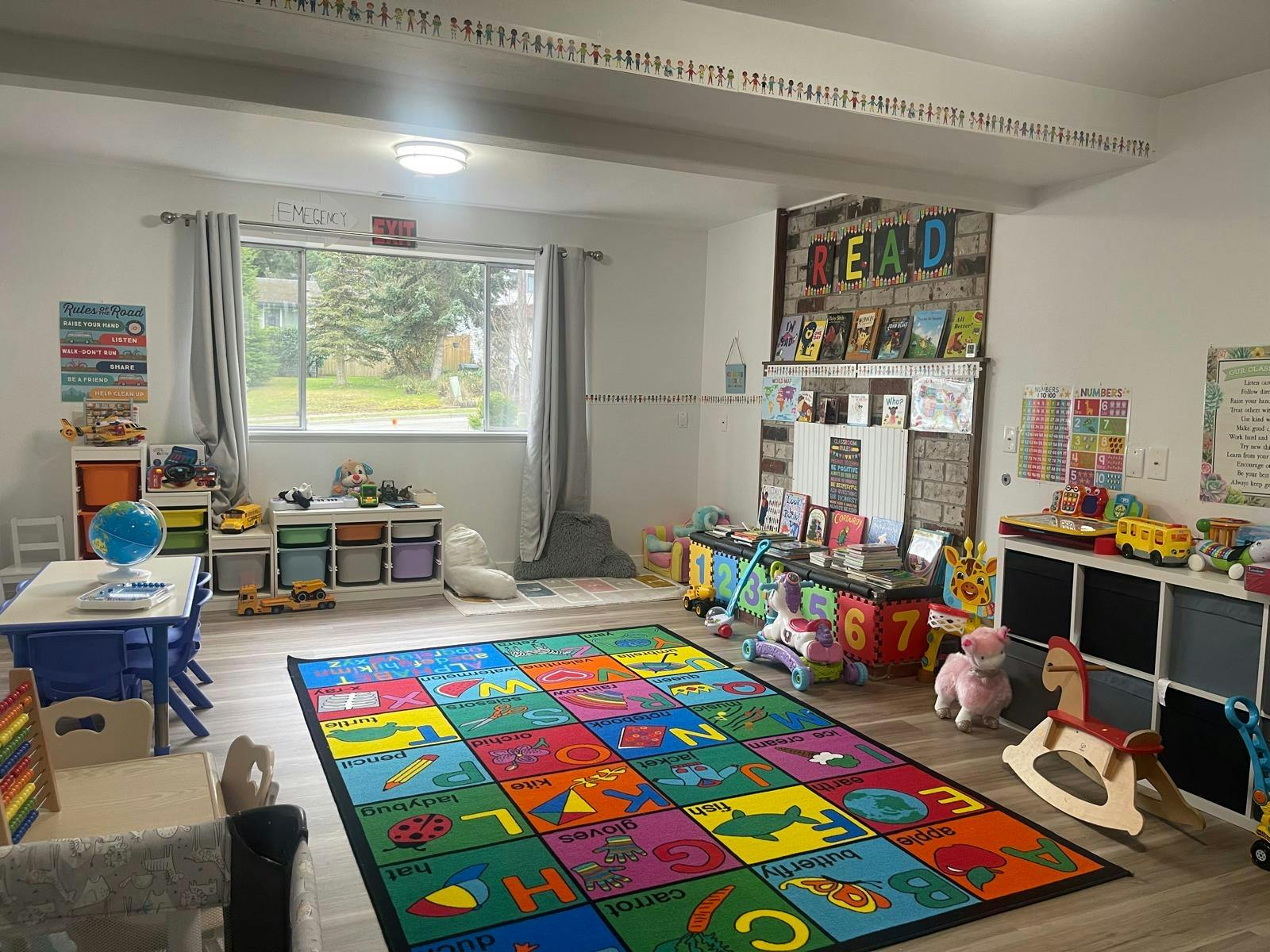 A colorful playroom with a large ABC rug, toys, and bookshelves